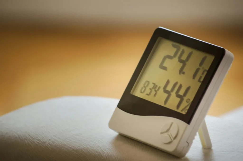 A small digital thermo-hygrometer on a stand showing 24.1 degrees and 44% relative humidity.