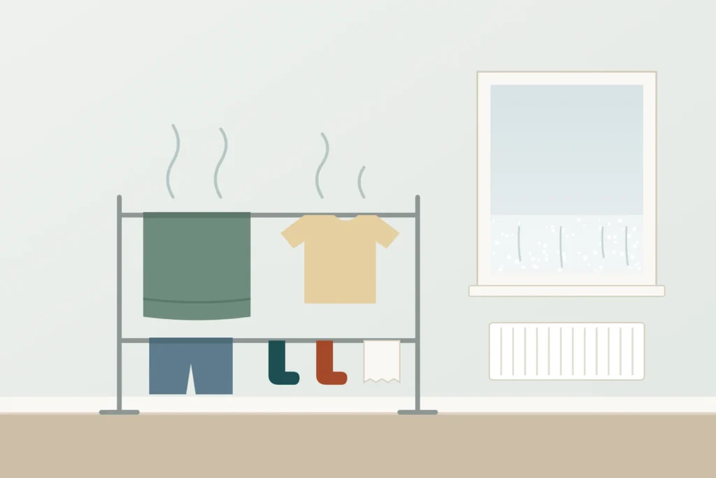 Illustration of wet laundry on a clothes horse giving off moisture, with water droplets misting the lower part of a nearby window.